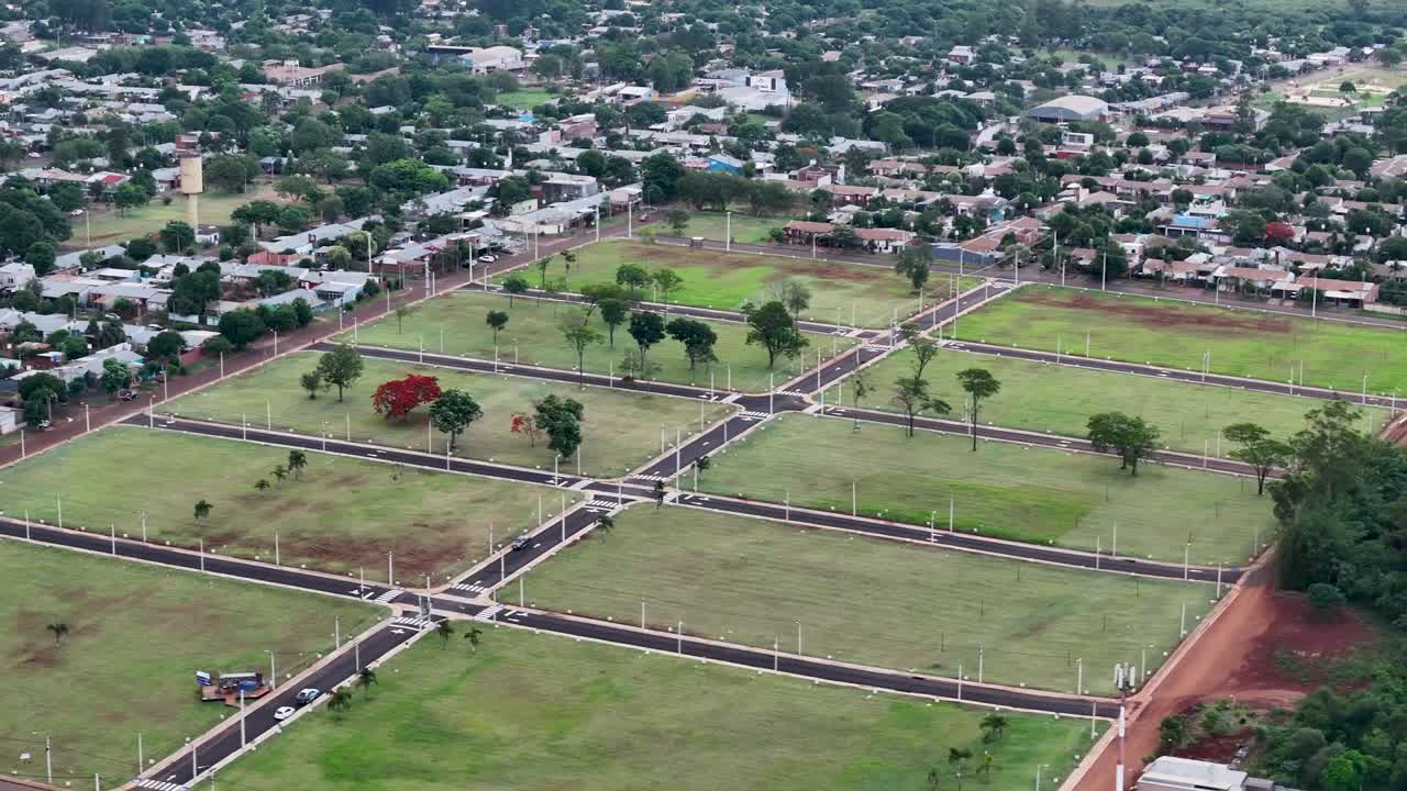 Drone pan over housing lots ready for construction in Posadas, Misiones, Argentina, revealing paved streets, sidewalks, and undeveloped plots within a growing suburban grid