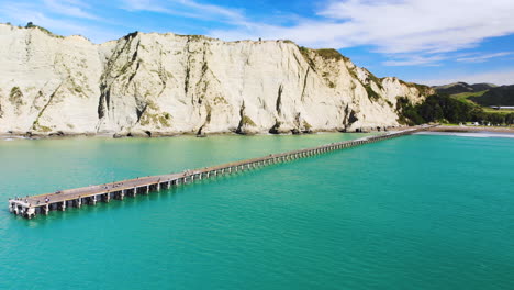 Vista-Aérea-Del-Muelle-De-La-Bahía-De-Tolaga-Con-Mar-Azul-Turquesa-En-La-Isla-Norte,-Nueva-Zelanda