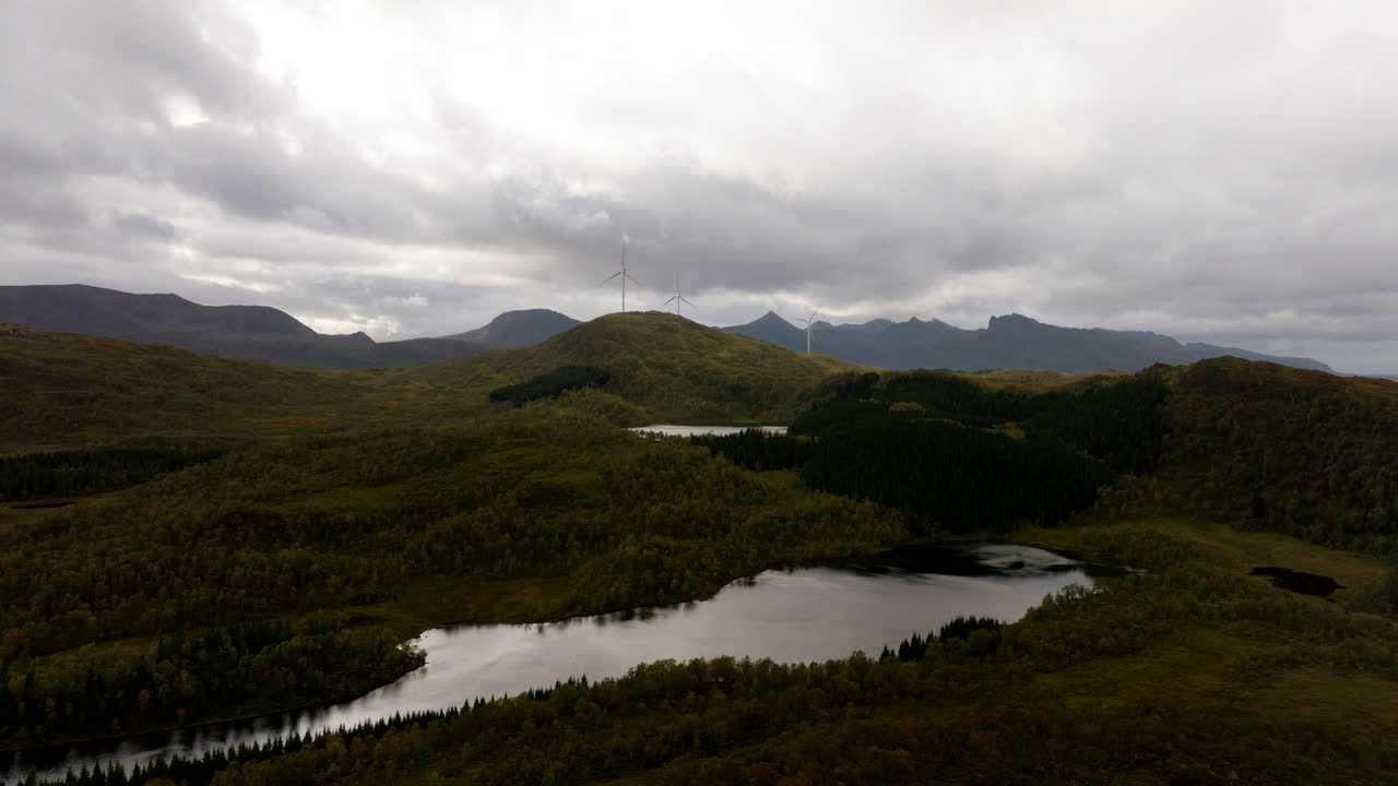 Wide drone view over lake of wind turbines in alpine landscape of Sortland