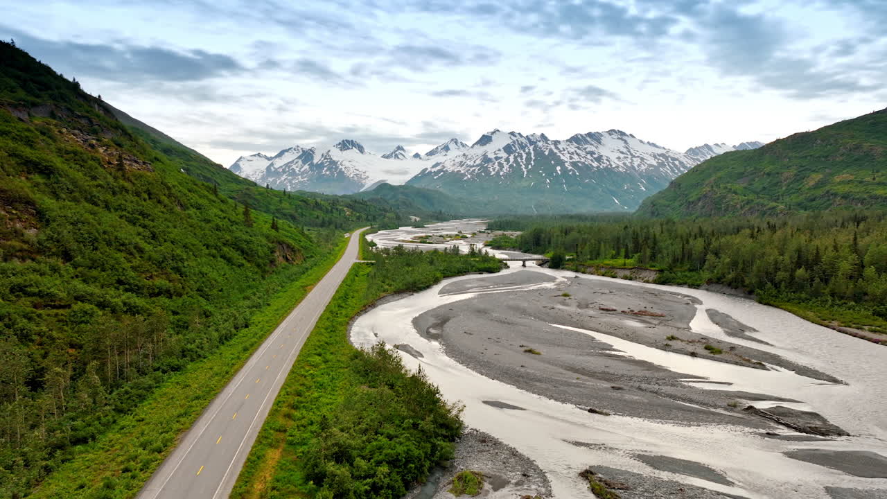 Alaska river and mountain road. Aerial highway following a winding river toward snow-capped Alaskan peaks