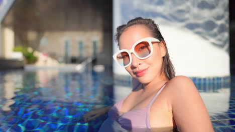 A-close-up-of-a-pretty-young-woman-leaning-along-the-shallow-end-of-a-swimming-pool