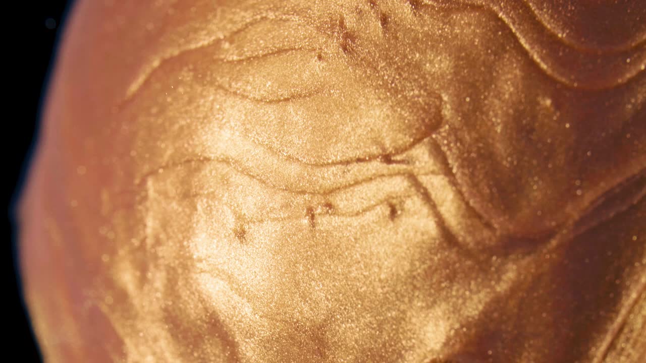 las partículas de tinta dorada fluyen en el agua como caramelo en la piruleta