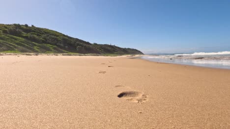 footprints leading towards the ocean on a beach