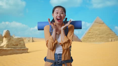 asian female hiker with mountaineering backpack saying wow while traveling in pyramid of giza