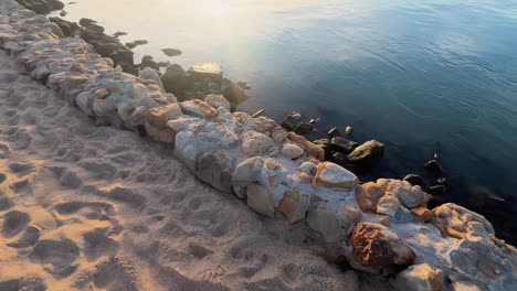 Spaziergang-Entlang-Der-Inselküste,-Sonnenuntergang-Nahe-Der-Wasseroberfläche-Und-Steinigem-Küstenweg,-Spiegelung-Des-Sonnenscheins,-Idyllische-Und-Friedliche-Naturlandschaft