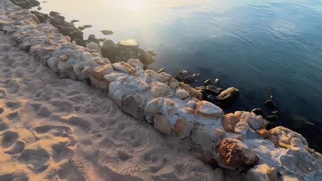 walk along island coast, sunset near the water surface and coastal stony pathway, reflection of sunshine, idyllic and peaceful natural scenery