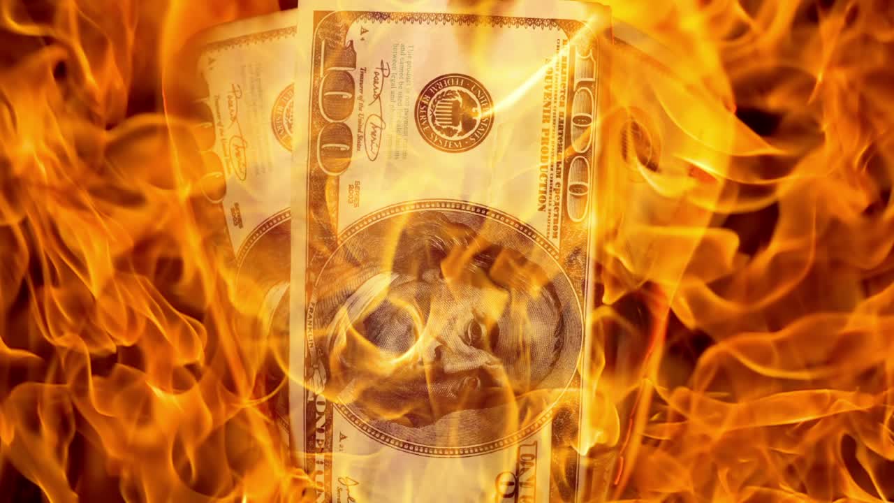 USA dollar bill money is burning in the fire, the concept of the economic crisis of inflation and currency devaluation.