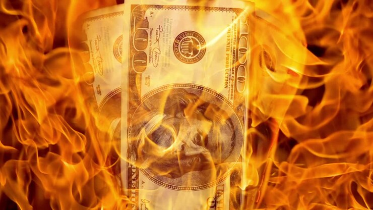 USA dollar bill money is burning in the fire, the concept of the economic crisis of inflation and currency devaluation.