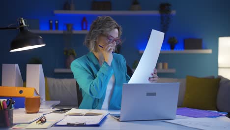 Home-office-worker-woman-smiling-at-camera-looking-at-paperwork.