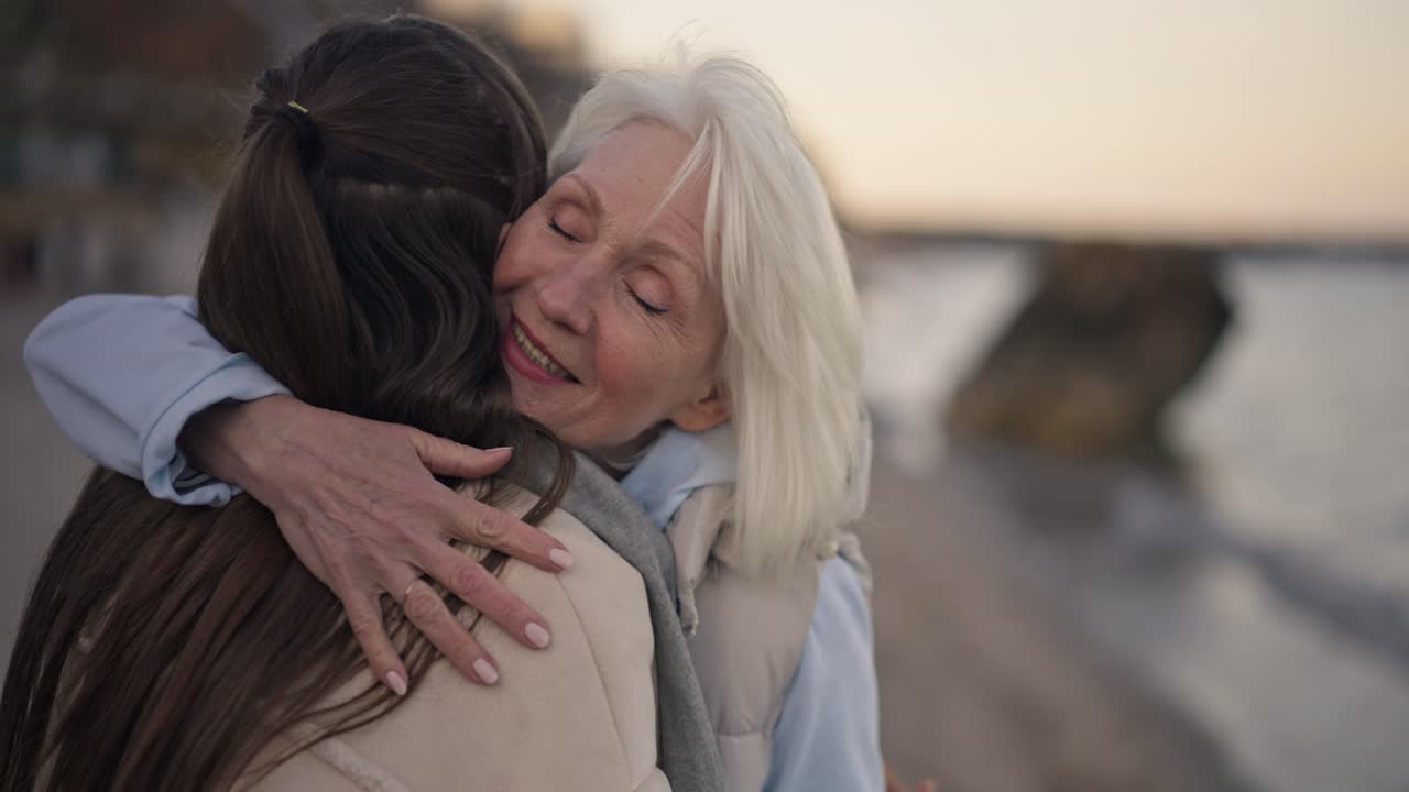 A grandmother and granddaughter hugging on the beach
