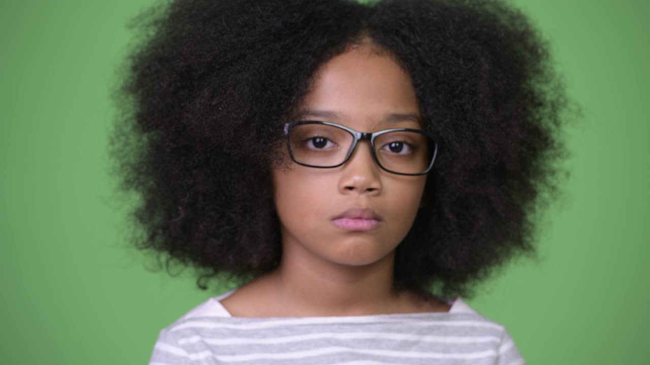 молодая милая африканская девушка с афро волосами на зеленом фоне