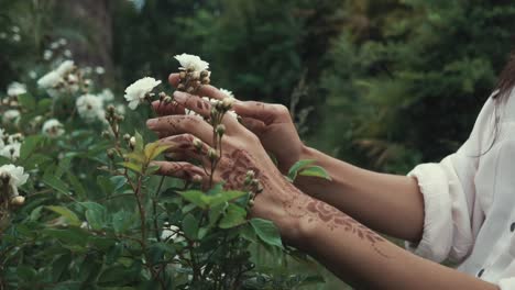 woman with henna tattoo examining white roses