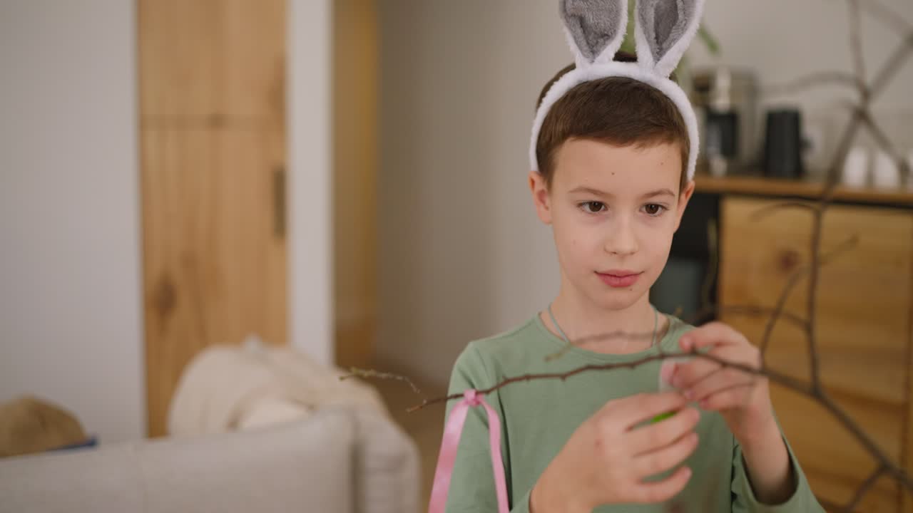 Boy decorating Easter branches with eggs