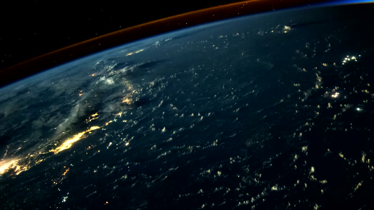 Clouds, as seen from space, cast long shadows on the water and cities of the Earth.  A lightning storm can be seen in the background.   Stills courtesy of the Earth Science and Remote Sensing Unit, NASA Johnson Space Center.  Processing by Rebus_Prod.