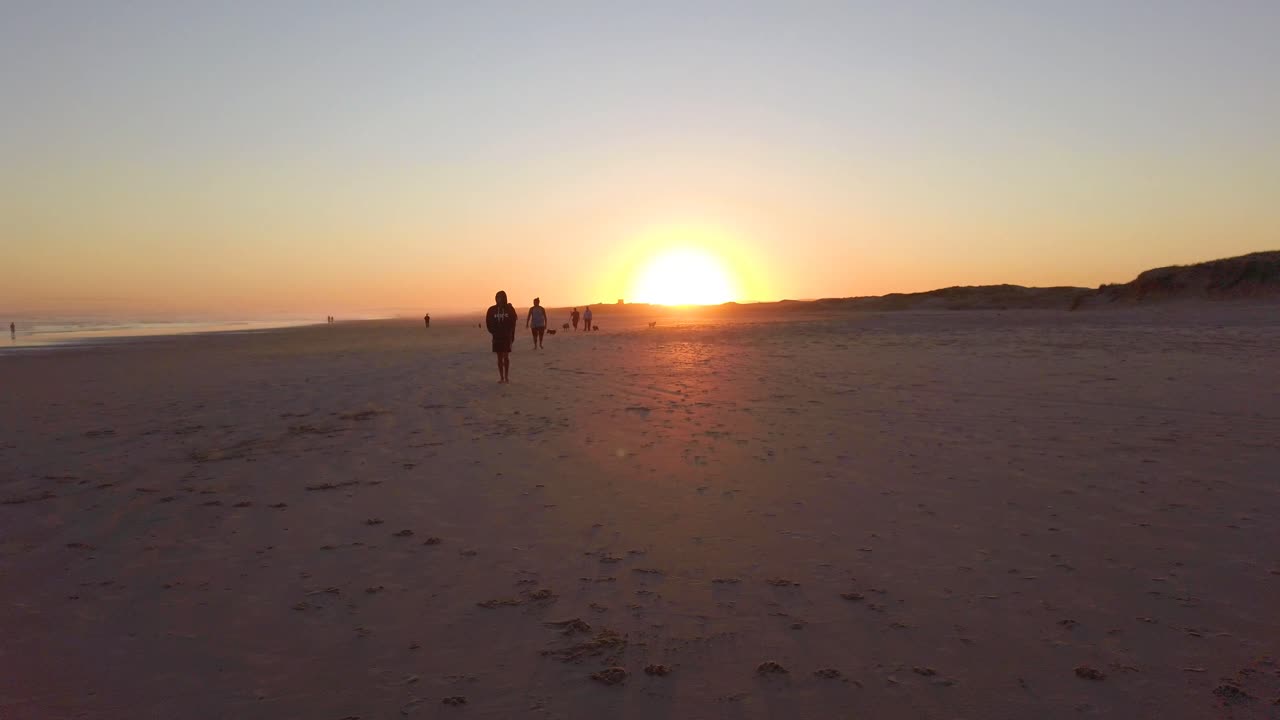 gente caminando por la playa al atardecer