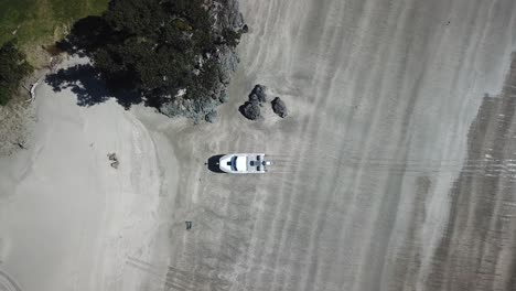 vista aérea de pájaro, de un barco anfibio en una playa de arena con una marca de pista creada a partir de viajar desde el mar