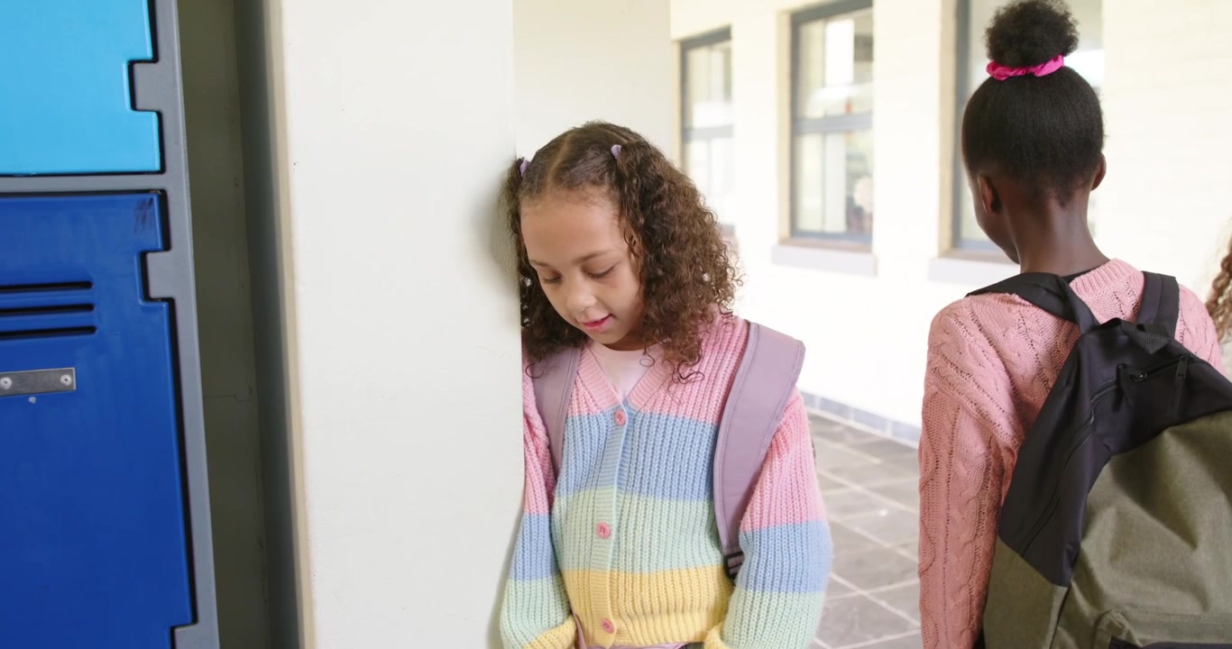 Teen girls walking hall blue lockers, peers with backpacks making striped girl leaning, copy space