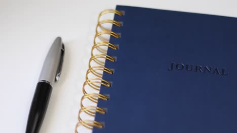 blue journal and black pen on white desk