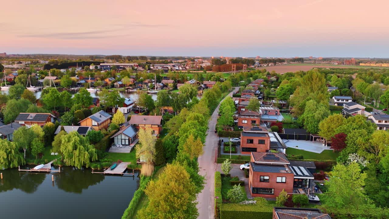 Flight over the village located on the water. Beautiful picturesque countryside with lush greenery at sunset time. Aerial view. Vinkeveen, the Netherlands.
