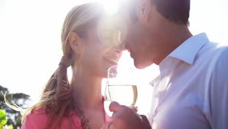 happy couple romancing while having a glass of wine in field