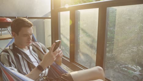 Man-Using-Mobile-Phone-In-A-Hammock---close-up