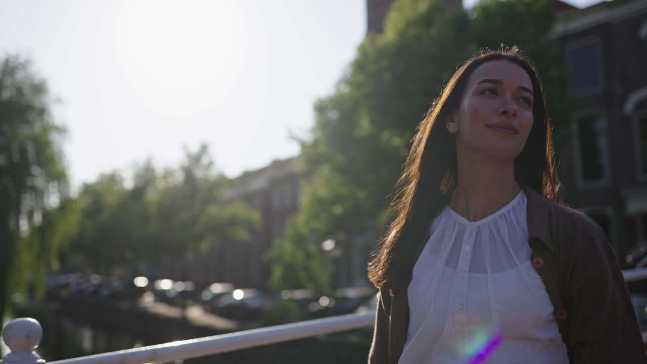 mujer modelo camina a lo largo del puente sobre el río en el distrito histórico de la ciudad urbana