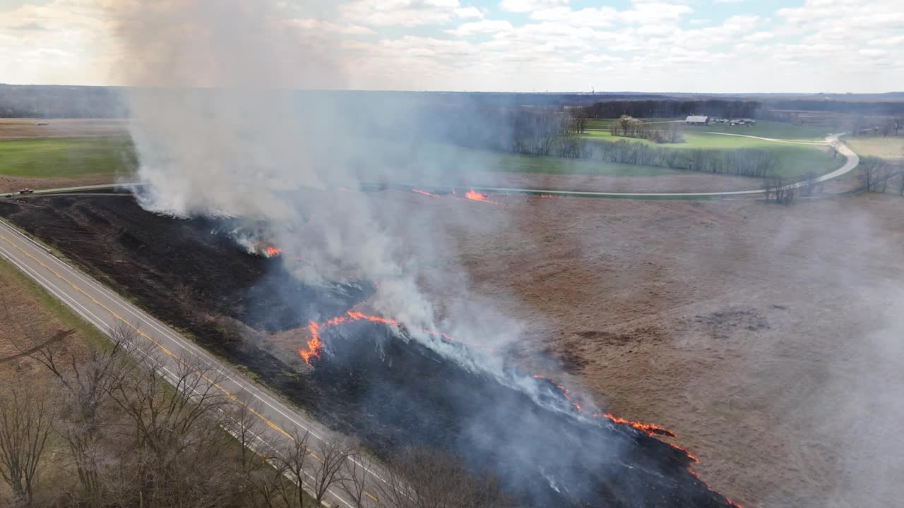 Smoke rises from field ablaze. Drone shot shows wildfire out of control. B-roll representative of Carolina fires.