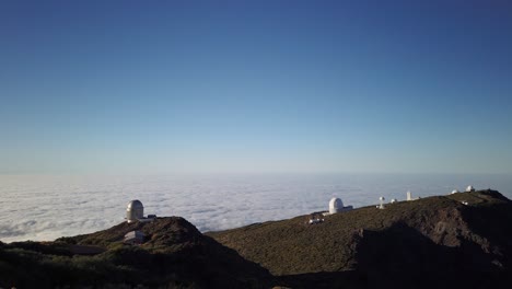 a time lapse of a group of telescopes in a mountain, over a sea of clouds