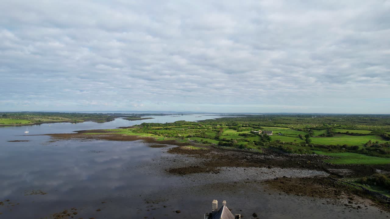 vista aérea de un avión no tripulado que revela el castillo de dunguaire y el paisaje circundante, irlanda