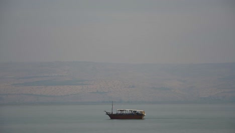 A-reproduction-of-a-2,000-year-old-fishing-boat-crosses-the-Sea-of-Galilee,-Israel-from-right-to-left