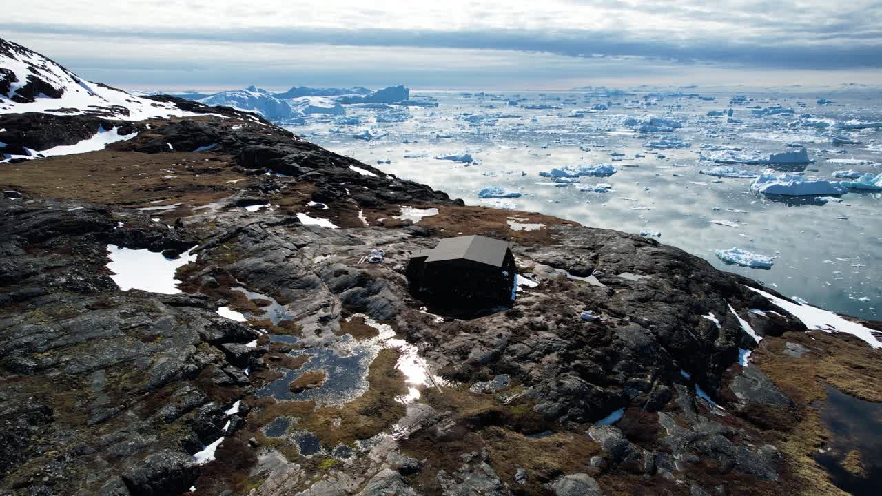 그린란드 지평선에 빙산이 있는 바위 절벽에 있는 외딴 역, 공중 궤도 전망