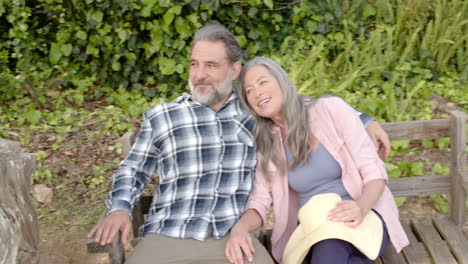 smiling mature couple relaxing on park bench, enjoying peaceful outdoor moment