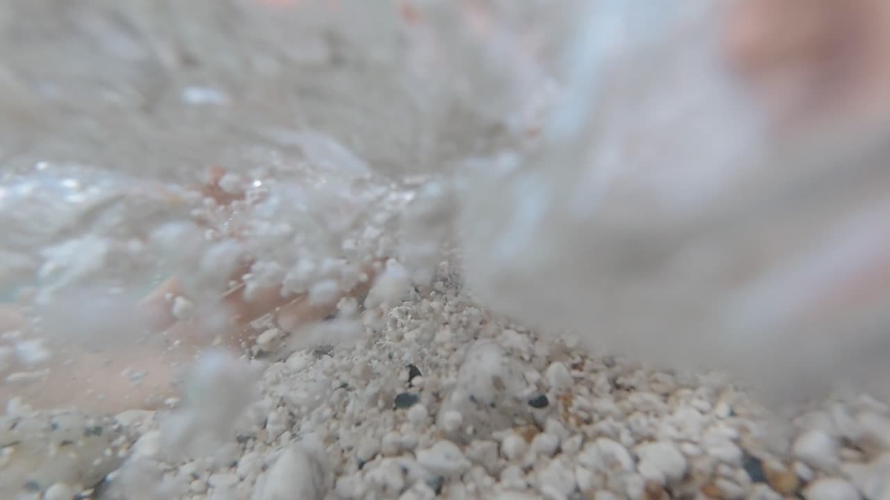 Slow Motion Underwater: Child's Hands Playing Over White Pebbles in Crystal Clear Sea