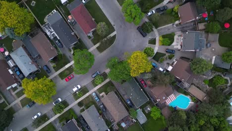 Urban-neighourhood-with-houses,-pools,-trees-and-cars-parked-on-street-with-properties-lined-by-fences