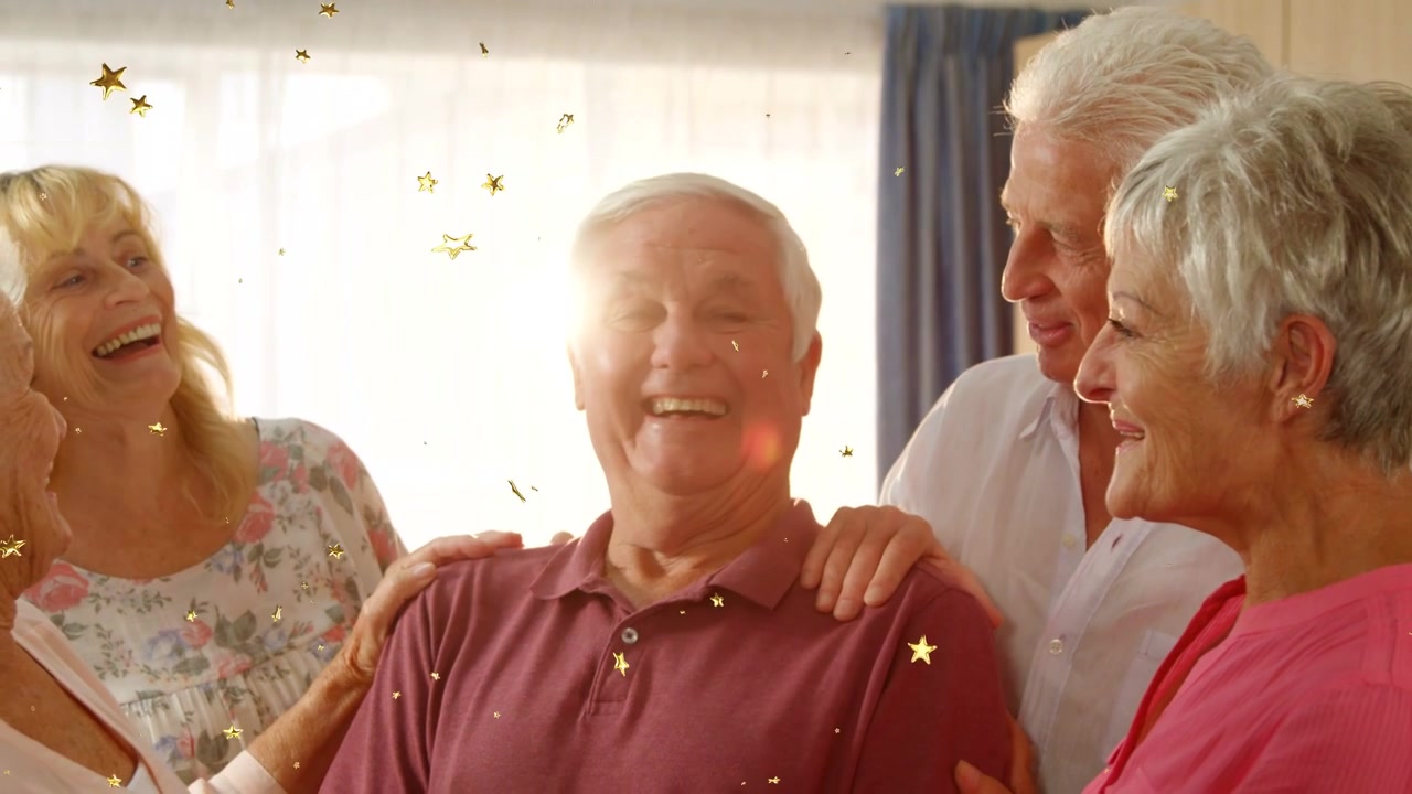 Famiglia anziana riunita vicino alla finestra, che festeggia un uomo, con coriandoli e bagliori dell'obiettivo per un'atmosfera di vita
