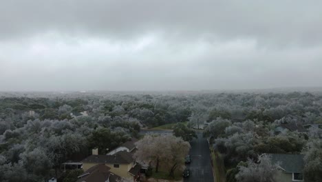 frozen icy trees in austin texas suburban neighborhood during cold winter freeze, aerial drone rise up over south austin homes