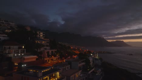 hotel o complejo de apartamentos en la orilla del mar al atardecer. forwards vuelan sobre el vecindario urbano después de la puesta del sol. ciudad del cabo, sudáfrica
