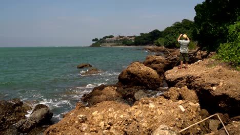 a man is taking pictures of a house by the sea on a smartphone