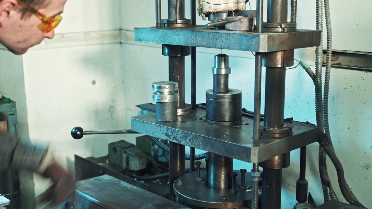 Man operating hydraulic press. Professional mechanic working with hydraulic press at factory