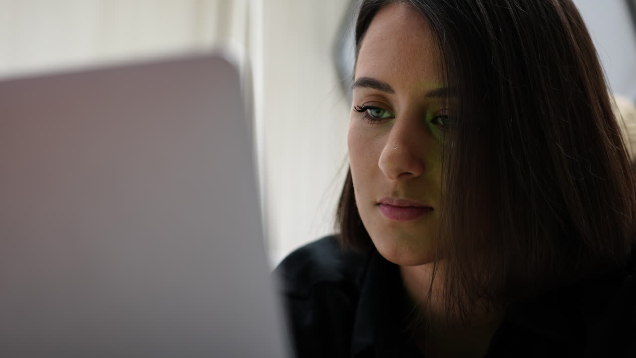 mujer joven frente a la pantalla del portátil, escribiendo y leyendo, de cerca