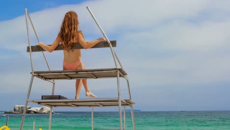 Rear-view-of-woman-sitting-on-observation-tower-on-the-beach-4k