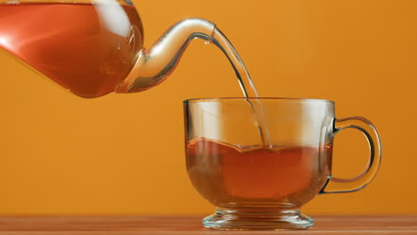 vertiendo té en una taza de vidrio