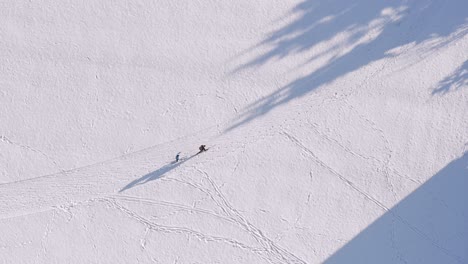 drone flight with to skiing people at a snowy white winter track, filmed straight from above, couple sports at the cross country track