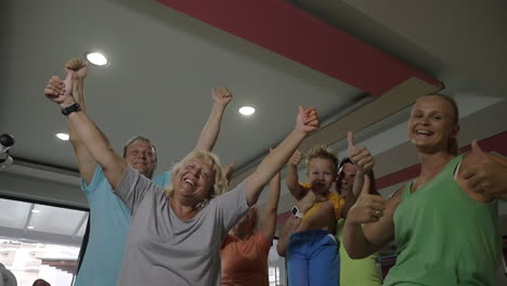 excited sporty family with thumbs-up in the gym