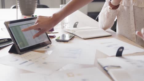 hands of diverse female colleagues in discussion using tablet in office, slow motion