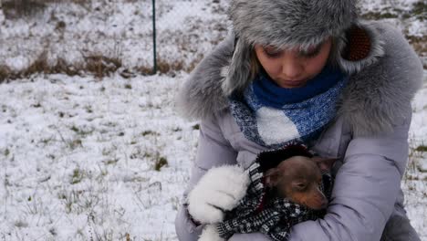 mujer preocupada cuidando de un perro pequeño durante el invierno