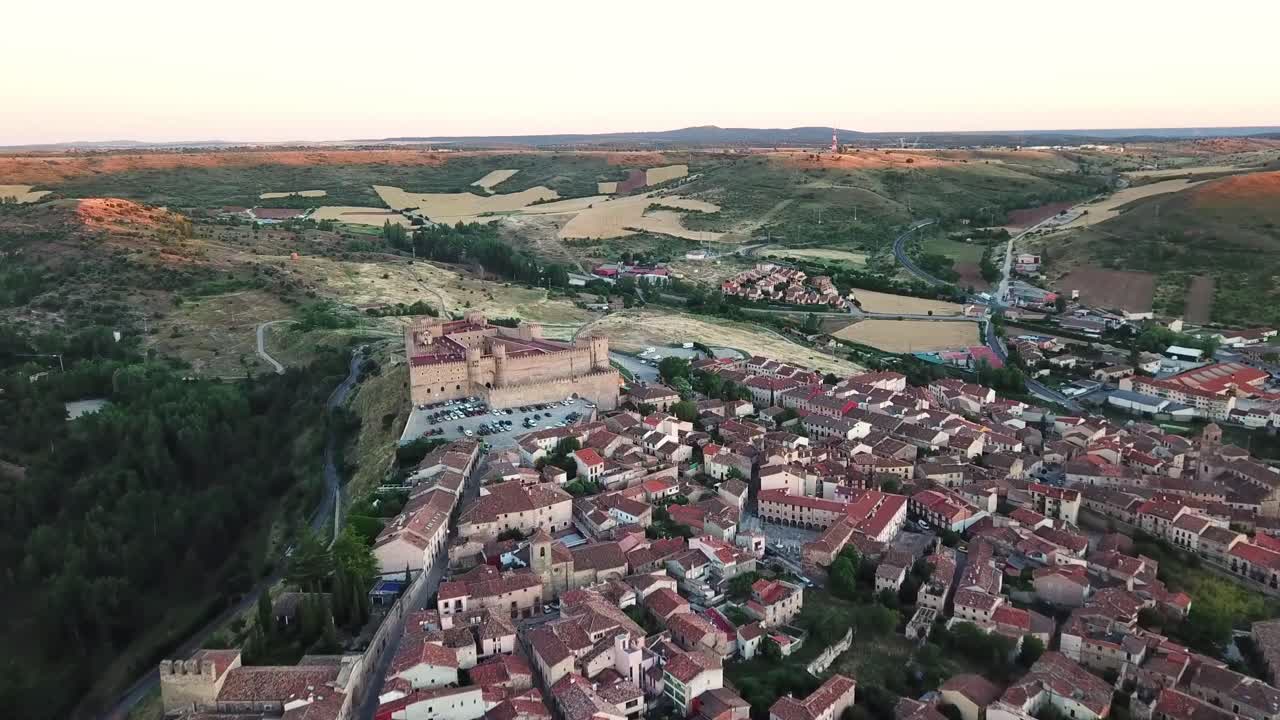 Aerial view of Sigüenza, Spain, featuring its medieval castle, traditional red-tiled rooftops, surrounding fields, and scenic landscape, offering a glimpse of this historic town's charm and heritage