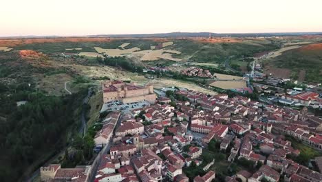 aerial view of sigüenza, spain, featuring its medieval castle, traditional red-tiled rooftops, surrounding fields, and scenic landscape, offering a glimpse of this historic town's charm and heritage