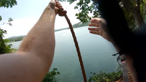 una toma de acción de punto de vista de un hombre blanco balanceándose en un columpio de cuerda en la orilla de un río y sumergiéndose en el río nilo en áfrica