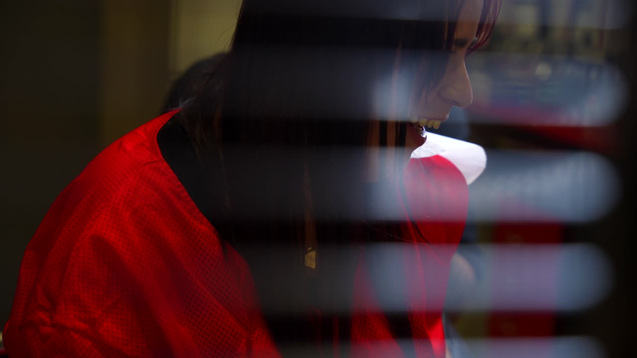 Panning left shot reveals a young woman laughing during a tattoo session